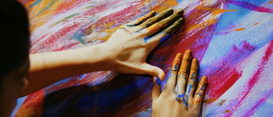 close up of hands painting a canvas in an abstract way